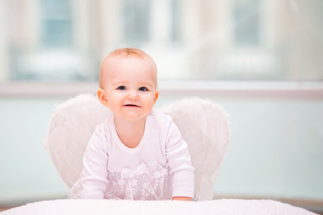 小一个活泼淘气的婴儿的肖像 长着白色的天使翅膀祈祷丘比特幼儿