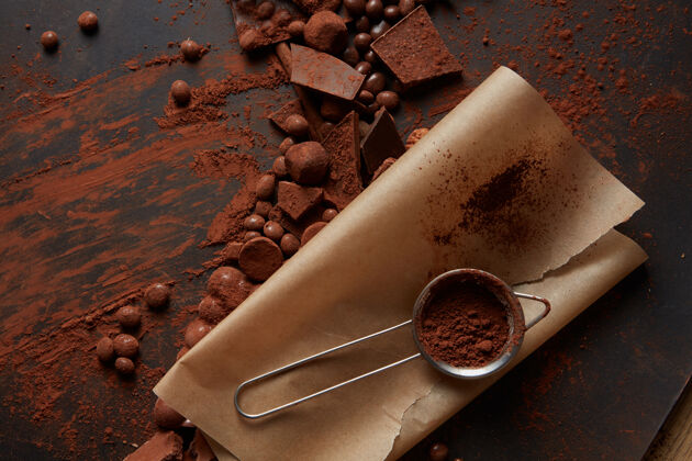 美味可可粉放在羊皮纸上的筛子里 巧克力放在深色的背景上剃须正方形治疗