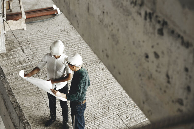 人一个成年的阿希特和他的工人在工地上谈论正在施工的建筑的俯视图头盔行政人员人