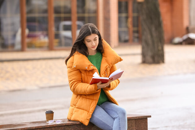 信息年轻女子在户外看书学习休闲咖啡