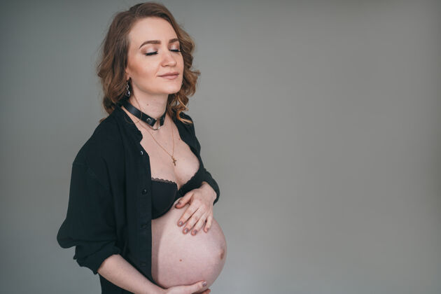 抱着一个穿着黑色内衣的怀孕女孩拿着肚子女人等待孩子的出生漂亮期望生活方式