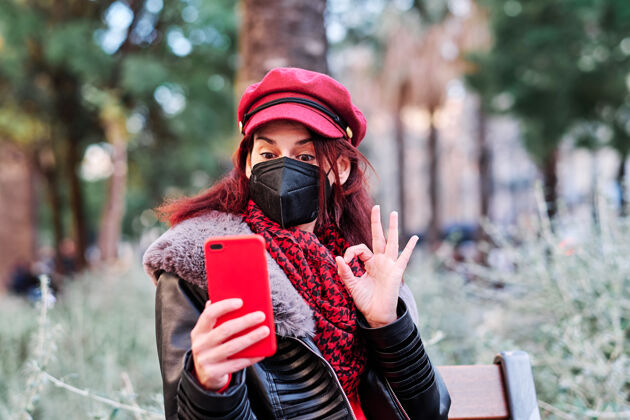 互联网戴着口罩用手机自拍的女人户外.新正常寿命城市概念概念聊天街道安全