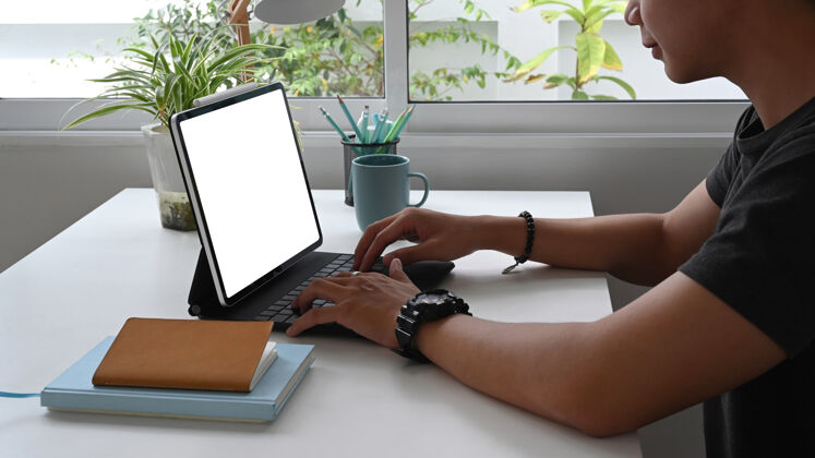 打字这位年轻的自由职业者坐在办公室里用白屏操作平板电脑通信创意连接