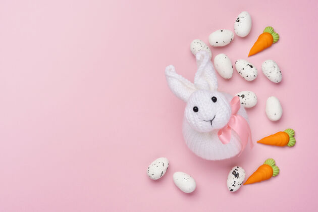 巢复活节春季贺卡 粉色上有兔子 鸡蛋和甜胡萝卜桌面查看羽毛快乐模糊