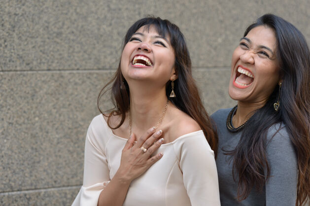 公司两位年轻的亚洲女商人在城市户外的合影城市景观幽默笑