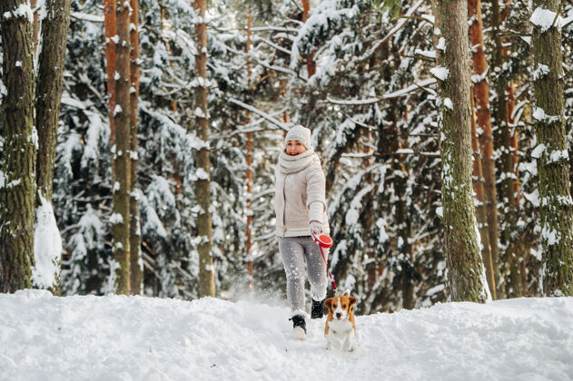 训练冬天带着狗散步的女人森林女主人在雪林里玩狗游戏微笑朋友人类的朋友