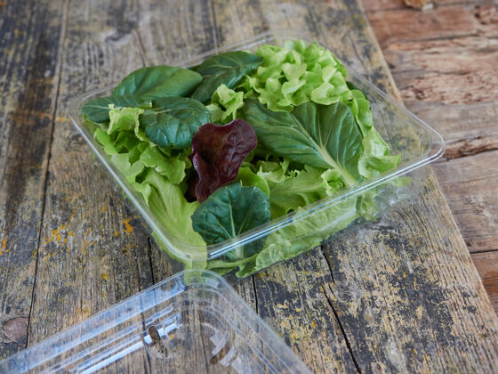 沙拉在木制表面的塑料包装上带走沙拉一次性健菜