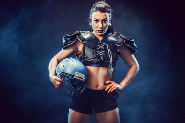 运动穿着性感制服的年轻黑发橄榄球运动员与球合影运动装性感身体
