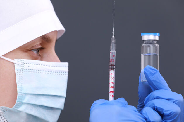 冠状病毒医生或护士戴着医用口罩和手套 正拿着注射器和流感 麻疹 冠状病毒疫苗在玻璃瓶中为疾病暴发接种疾病实验室婴儿