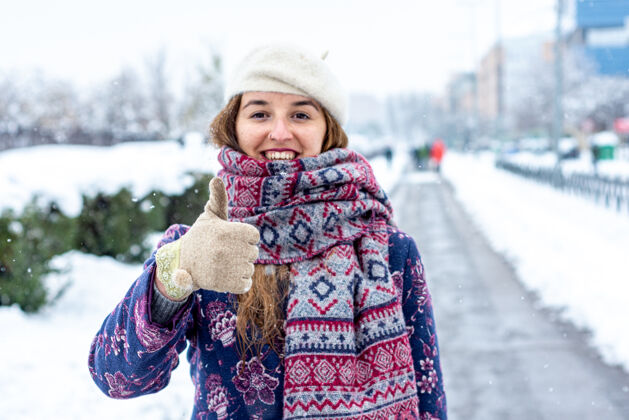 快乐一个年轻的金发女人穿着冬装在城市的雪地大道上的肖像城市街道外套冬天