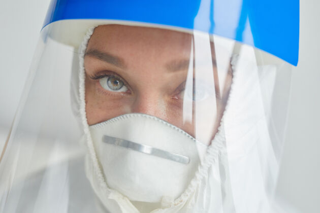病毒年轻医生戴着呼吸和透明塑料防护口罩在白墙上的头像医疗设备感染医学和科学