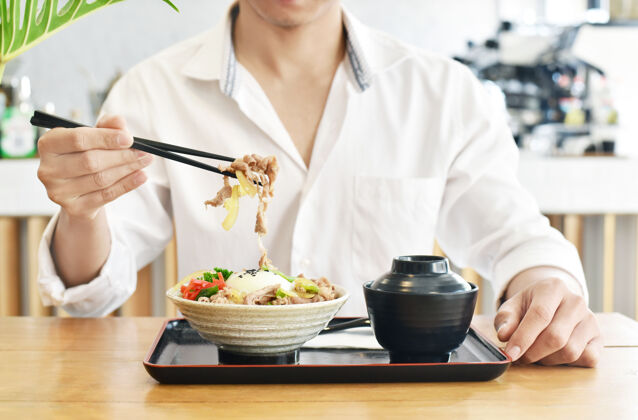 烹饪特写吃人gyudon或日本菜牛肉碗午餐健康特写