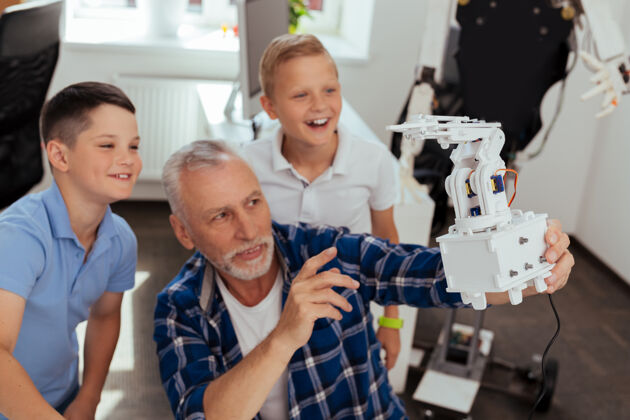 孩子网络时代一个现代机器人的选择性焦点在一个快乐的老人手里教育机械班级