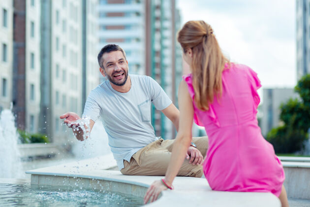关系快乐的心情快乐的男人一边玩水一边看着他的女朋友休息公寓散步