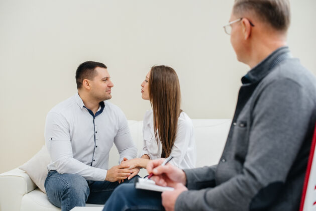 同情一对年轻幸福的已婚男女在一次心理治疗中与一位心理学家交谈心理学问题访问咨询师