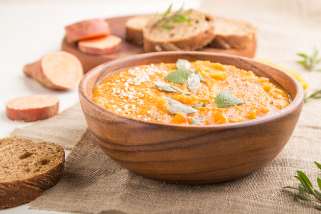 草药红薯或巴塔塔奶油汤芝麻在一个木制碗在一个白色的木制表面亚麻织物木材盘子蔬菜