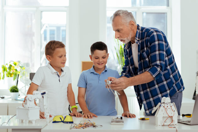 童年家庭时间一个和蔼可亲的男人一边给孙子们看机器人一边和他们聊天社会保障经验机械