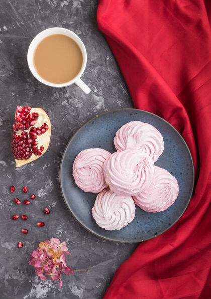 蛋糕粉红石榴自制的西风或棉花糖与咖啡杯在黑色混凝土表面与红色纺织品糕点面包房糖果