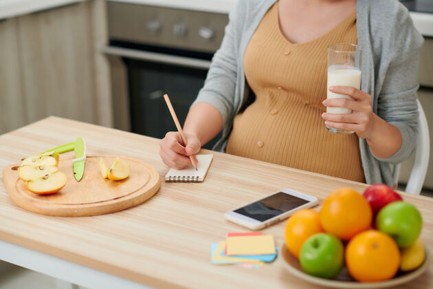 房子孕妇抱着玻璃奶瓶在厨房摆准妈妈的姿势肚子在线饮食