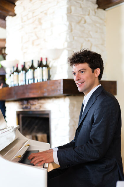 钢琴家钢琴手在钢琴上创造了一个美丽的音乐氛围在一个精致的餐厅微笑人白种人