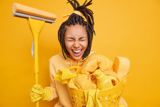 编织做家务的男人拿着拖把在家里洗地板 提着一篮子的洗衣篮 篮子里的清洁剂被隔离在黄色的地方喜悦立场家庭主妇