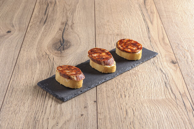 午餐特写镜头的克罗斯蒂尼与西班牙香肠的顶部镀在一个黑暗的钢板肉盘子面包