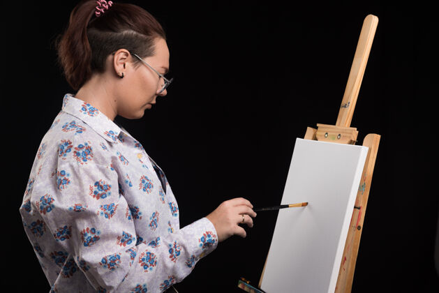 成人女画家用黑色的铅笔在画布上画画画家画布手