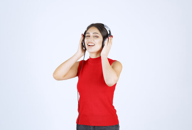 服装穿着红衬衫的Dj女孩戴着耳机 听着好听的音乐年轻人休闲享受