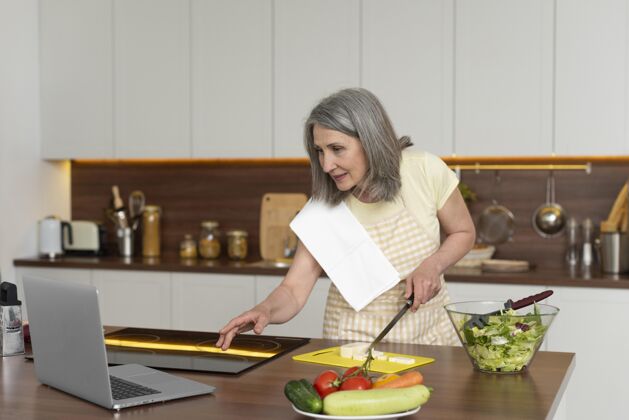 女人家里的老太太在厨房用笔记本电脑上烹饪课厨房老年人老年人