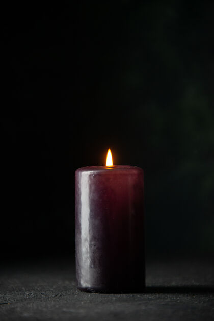 烛光黑暗中紫色蜡烛的正视图蜡烛打蜡火