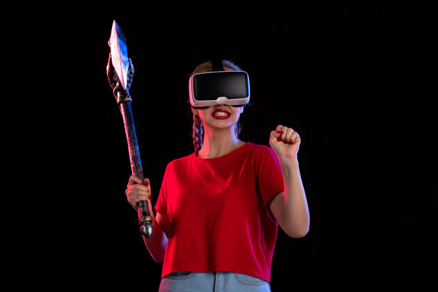 玩美丽的女性玩虚拟现实与战斧黑暗的前视图虚拟现实人战斗