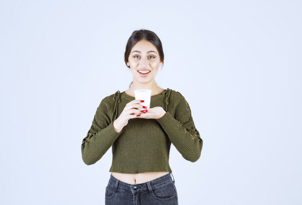 摆姿势一个年轻漂亮的女模特手里拿着一个装着热饮的塑料杯年轻漂亮杯子