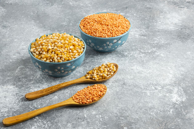 堆两碗玉米粒和红扁豆放在大理石表面玉米碗豆类