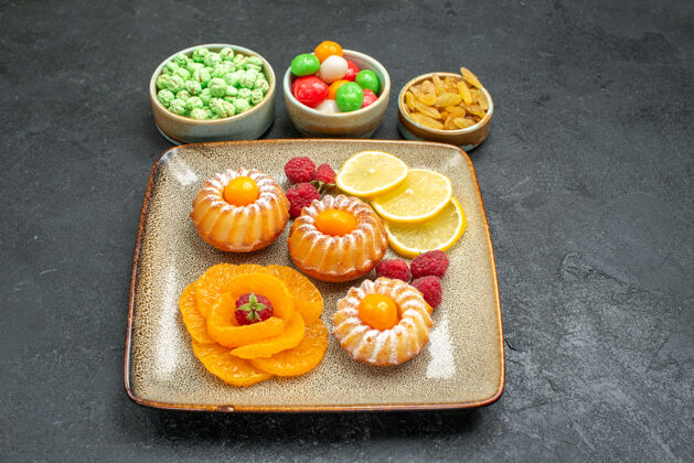 食物前视小蛋糕柠檬片橘子和糖果在黑暗的空间盘子小蛋糕托盘