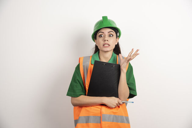 女商人一个戴着绿色头盔 拿着剪贴板站着的震惊的女建造师高质量的照片主管工作女性