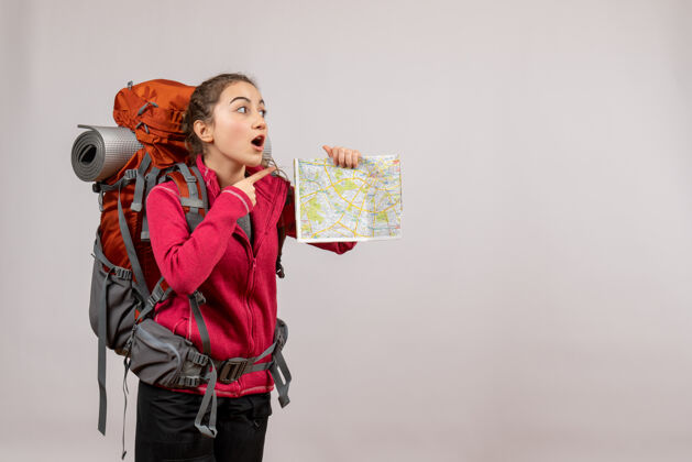 成人带着大背包的年轻旅行者惊讶地举着地图在灰色的孤岛上灰色地图大