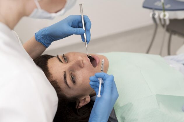 正畸医生在牙医那里做手术的女病人面罩过程专业
