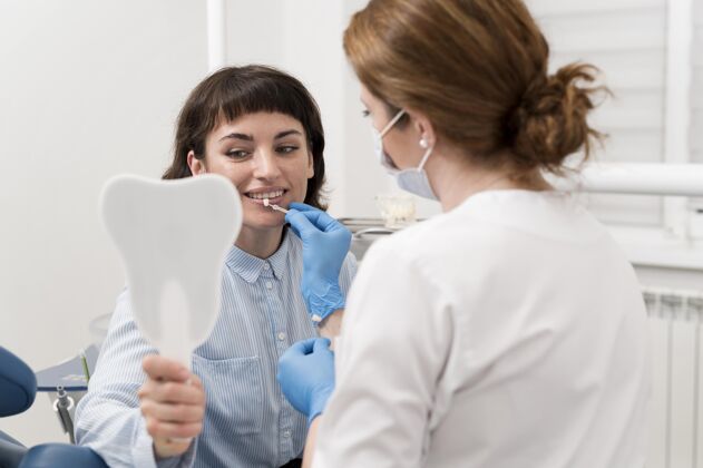 妇女女病人在牙科诊所照镜子过程雇员从业者