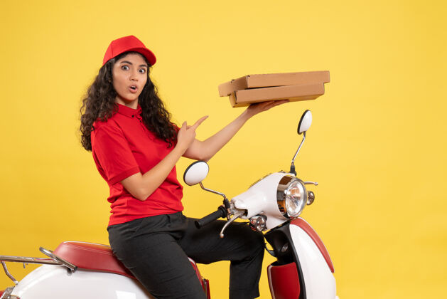 盒子前视图骑自行车的女快递员拿着黄色背景的披萨盒工作服工作服工作人持有工人
