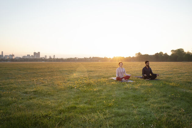 专注男人和女人一起在户外做瑜伽外面冥想水平
