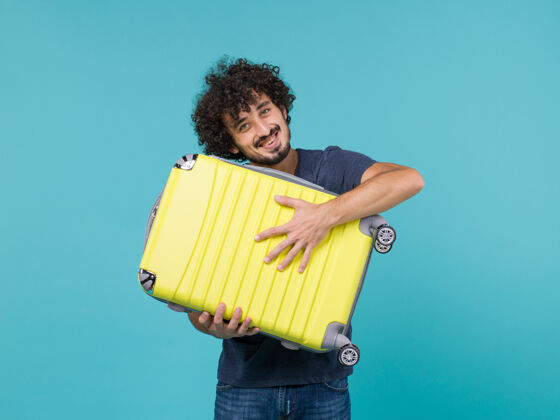 包度假的男人拿着蓝色的大黄色手提箱旅行蓝色持有