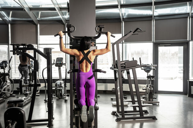 手年轻肌肉发达的女人在健身房练习设备举重健身杠铃
