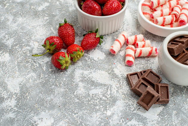 壁板在灰白色桌子的右边 下半部分是草莓巧克力糖果和一些草莓巧克力糖果的碗成熟草莓食物
