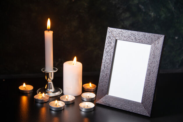 烛光燃烧的蜡烛作为一个在黑色的表面下降记忆的正面视图视图宗教火