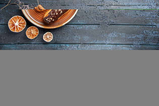干的俯视图巧克力eclairs在椭圆形板干花枝和干柠檬在黑色木桌左侧与复制空间百分比椒盐卷饼深色