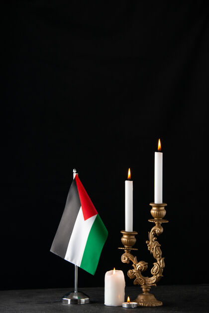 火焰在黑暗的表面上燃烧着巴勒斯坦国旗的蜡烛的正面图烛台死亡视野