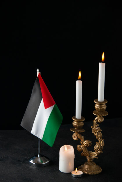 黑暗在黑暗的表面上燃烧着巴勒斯坦国旗的蜡烛的正面图正面死亡风景