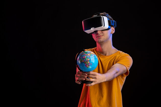 地球在黑暗的表面上玩虚拟现实拿着地球仪的年轻男性世界现实玩家
