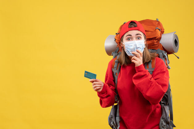 面具正面图年轻的女徒步旅行者背着背包和面具拿着折扣卡背包交流抱着
