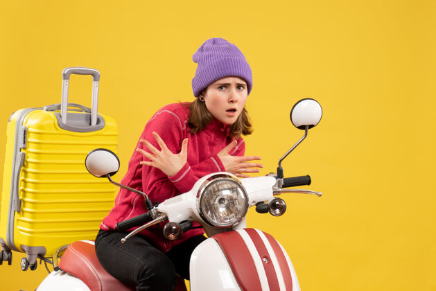 轻便摩托车前视图吓坏了那个戴着紫色帽子骑着轻便摩托车的年轻女孩摩托车吓坏了前面
